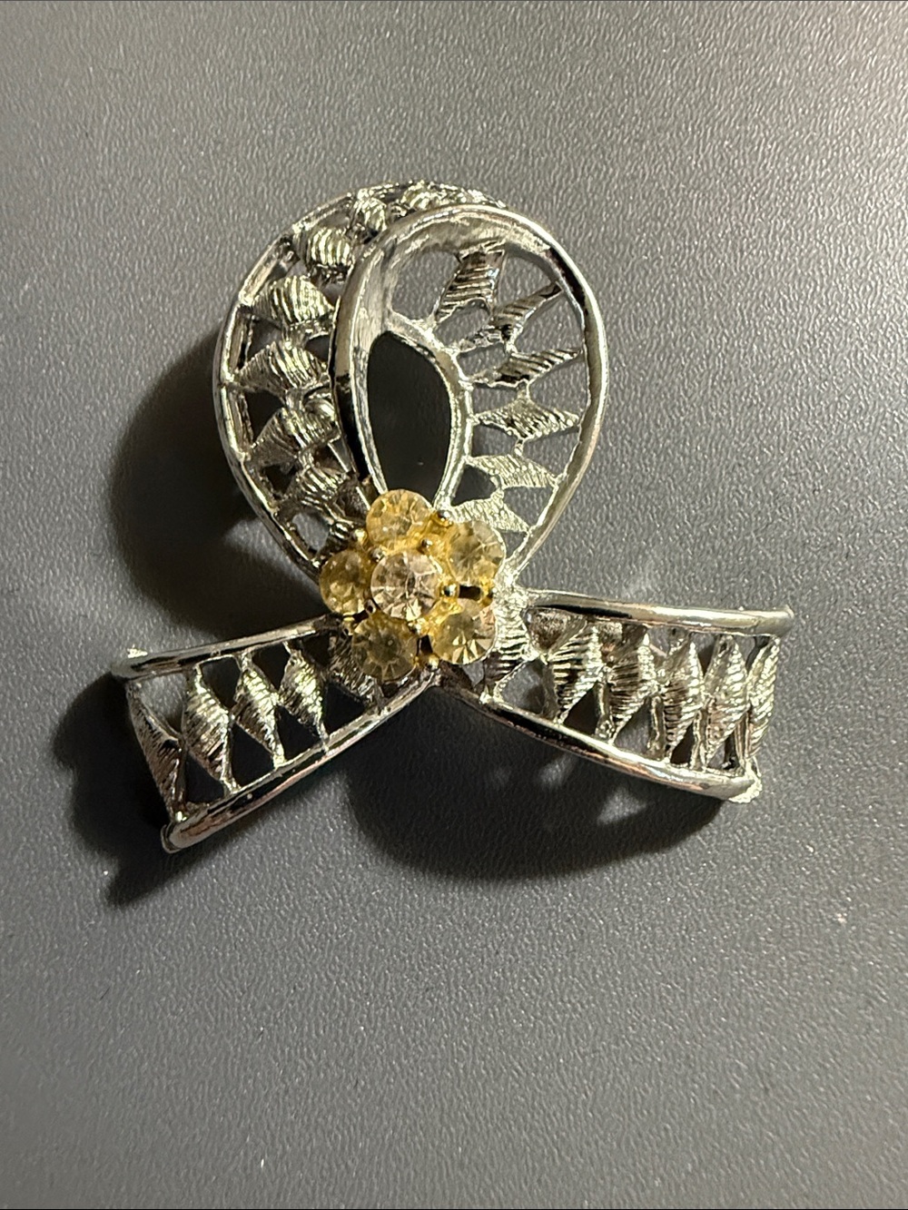 ribbon-shaped brooch features a silvertone